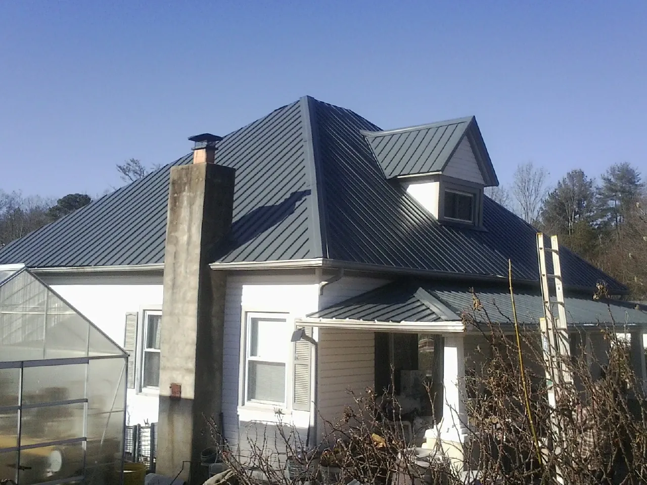 Dark blue standing seam metal roof on a white farmhouse with dormer — Slate & Tile Roof Repair by Roofing Brothers in Coeymans