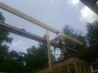 Carpenter setting a ridge beam over a new addition frame — Ice Dam Removal by Roofing Brothers in Coeymans