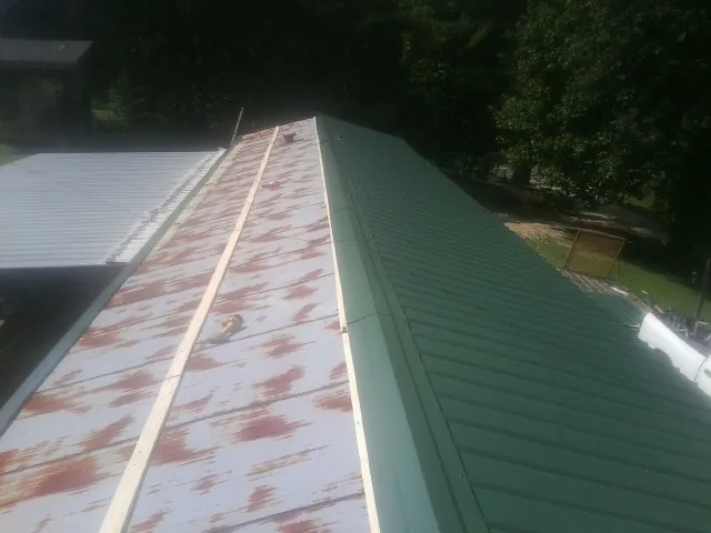 Old rusted panels beside newly installed green metal roofing — Wind Damage Roof Repair by Roofing Brothers in Coeymans