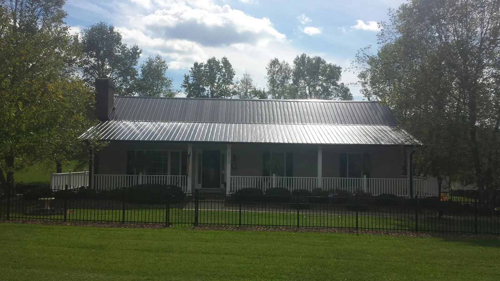 Gray metal roof on a brick ranch with a full width front porch — Gutter Guard Installation work by our crew in Coeymans