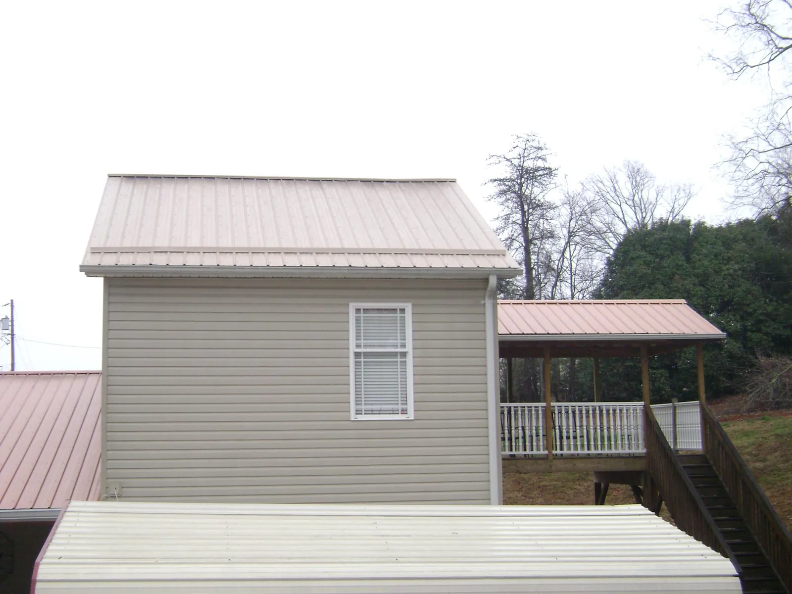 Tan metal roofs on a two story addition and attached porch, from a Roof Replacement job in Coeymans