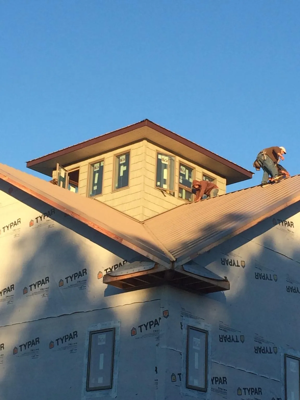 Roofers working around a rooftop cupola on a new metal roof at sunset — Roof Waterproofing in Coeymans by Roofing Brothers